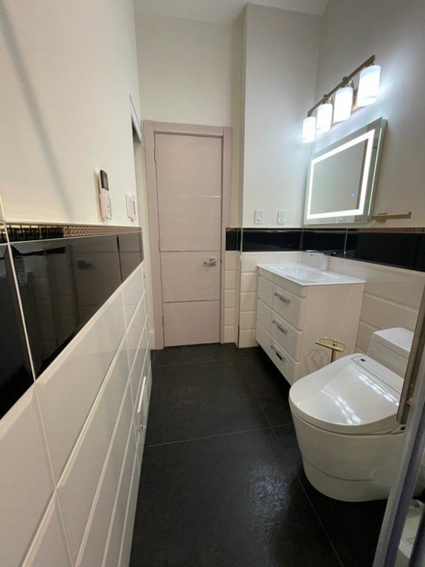 Black and white bath with smart toilet and lit mirror
