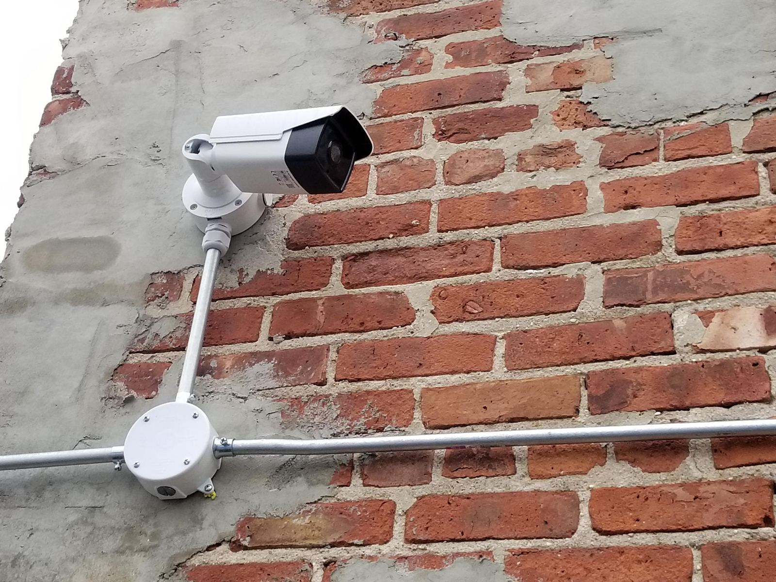 Security camera with conduit on a brick wall
