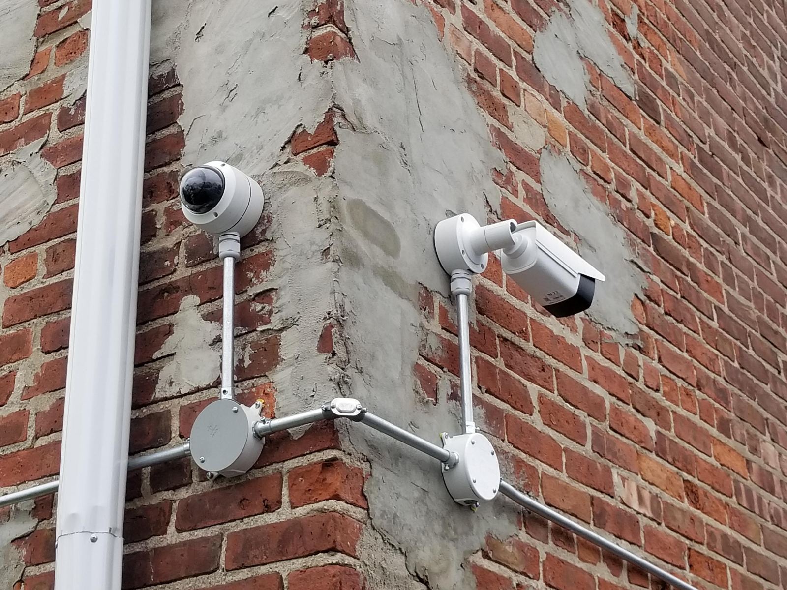 Dome and bullet cameras on a building corner with conduit