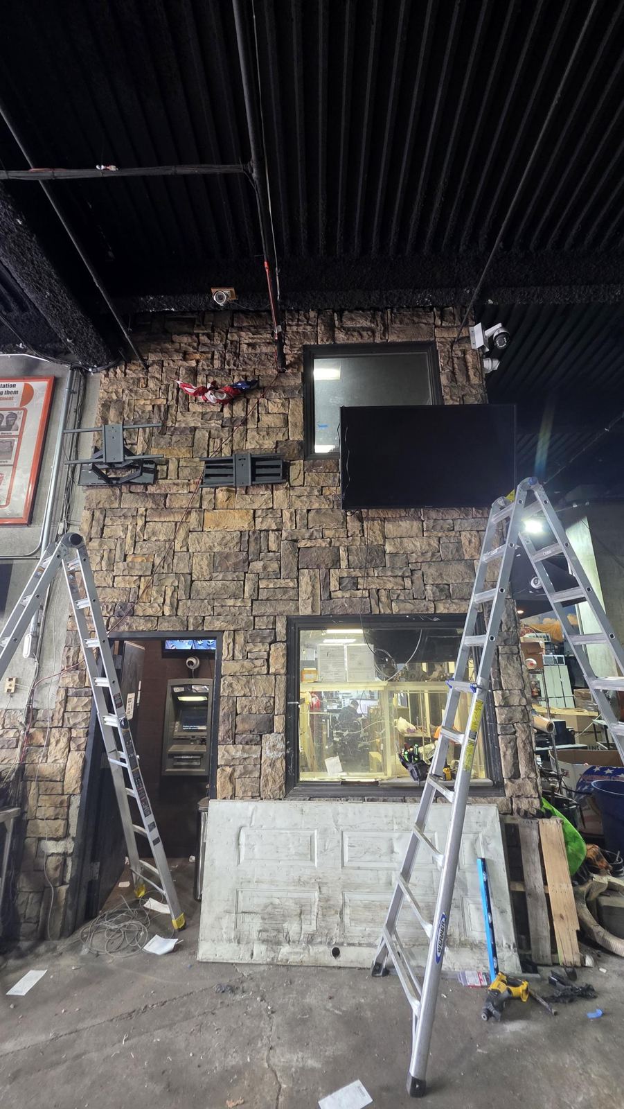 Display mounts and cameras installed on a stone wall in a commercial facility
