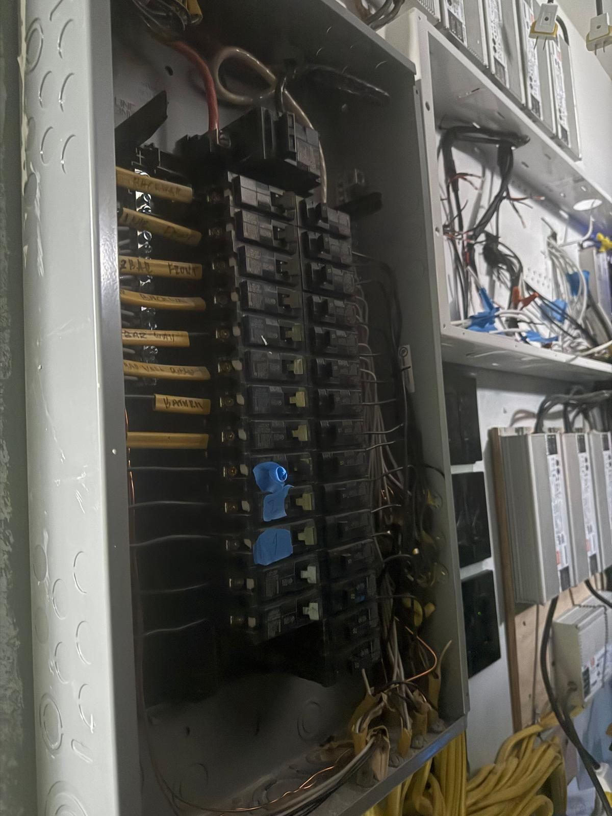 Electrical panel with labeled circuits next to lighting drivers