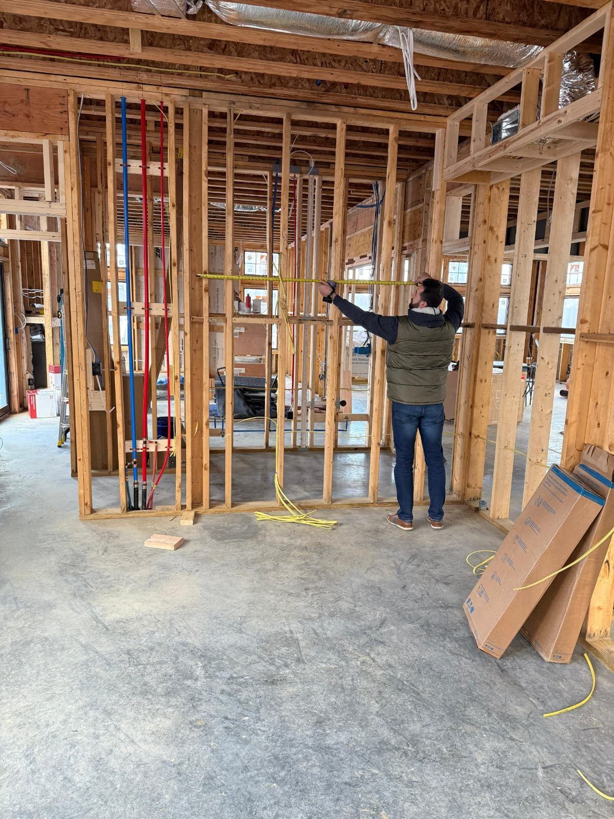 Contractor measuring inside new framing with plumbing lines run