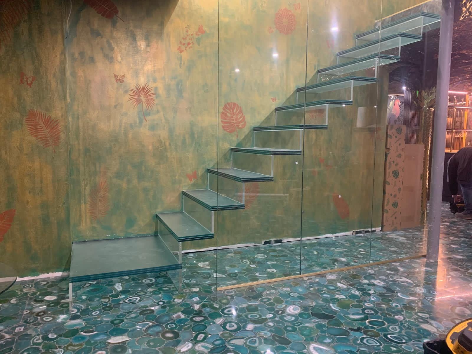 Cantilevered glass stair over a backlit agate floor
