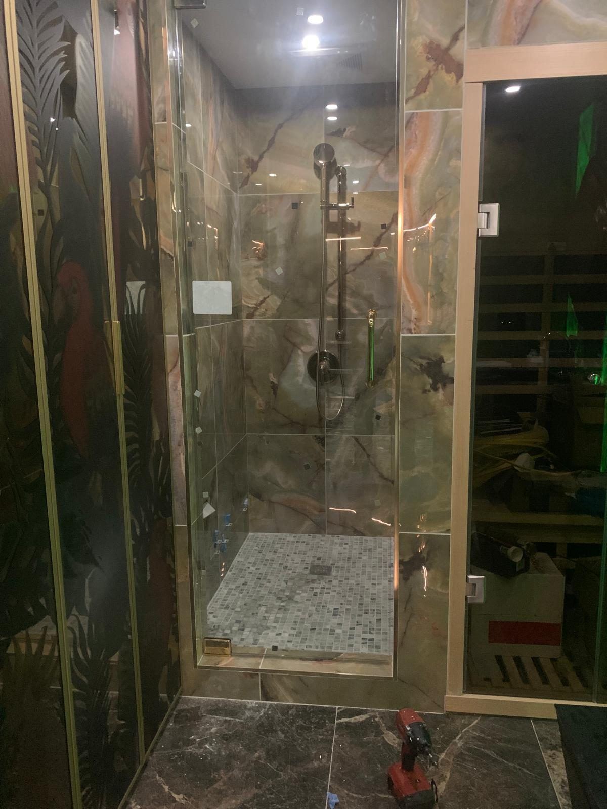 Onyx-tiled shower beside an infrared sauna