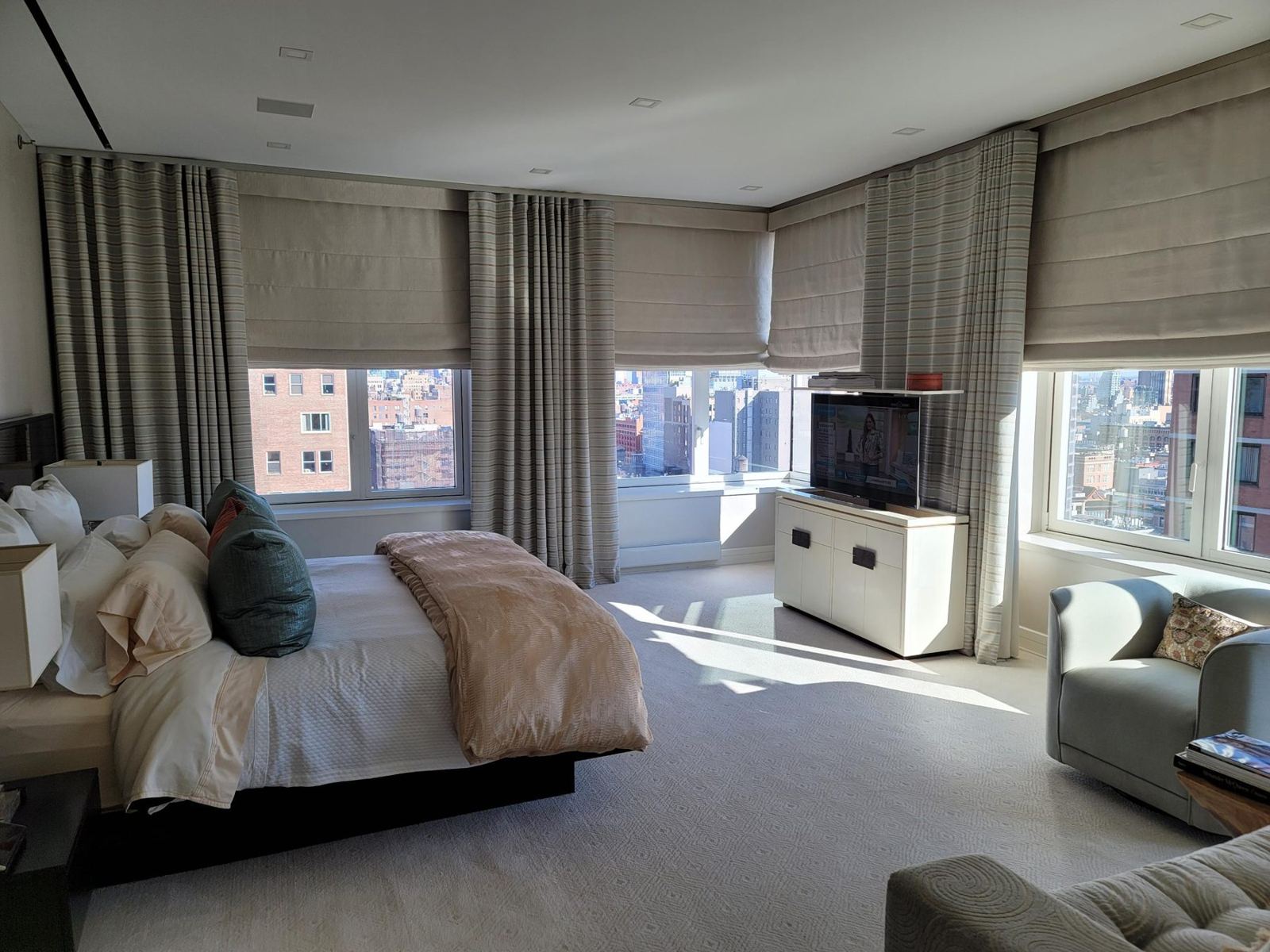Corner bedroom with Roman shades and a pop-up TV cabinet