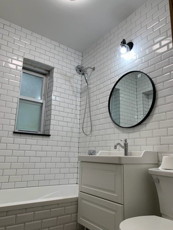 Beveled subway tile bath with round mirror