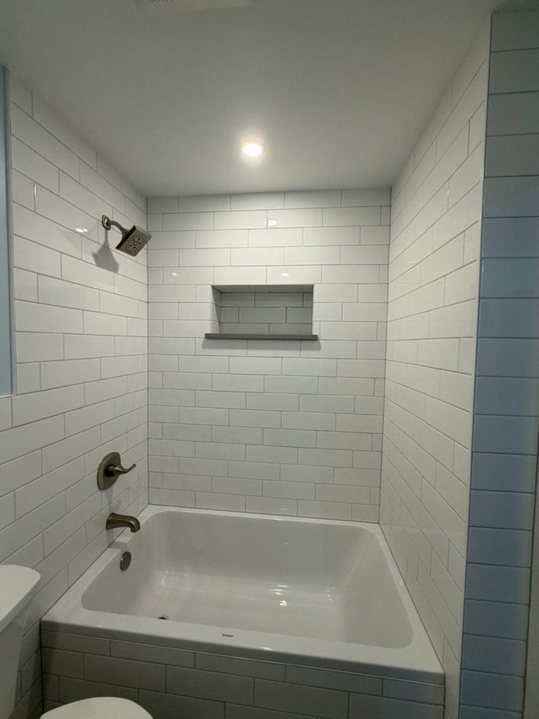 Deep soaking tub with subway tile surround and niche