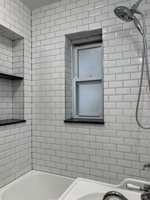 Subway tile shower with recessed shelves and tiled window return