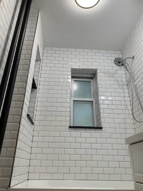 Floor-to-ceiling subway tile around a shower window